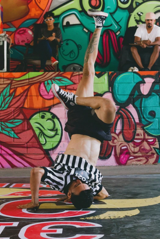 a young man is doing a handstand in front of a graffiti wall