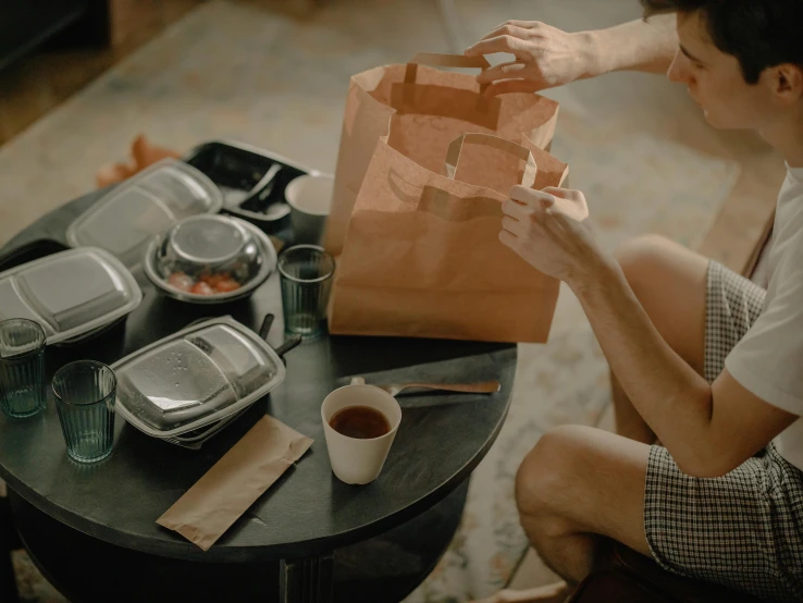 a man sitting at a table with a bag on his knees