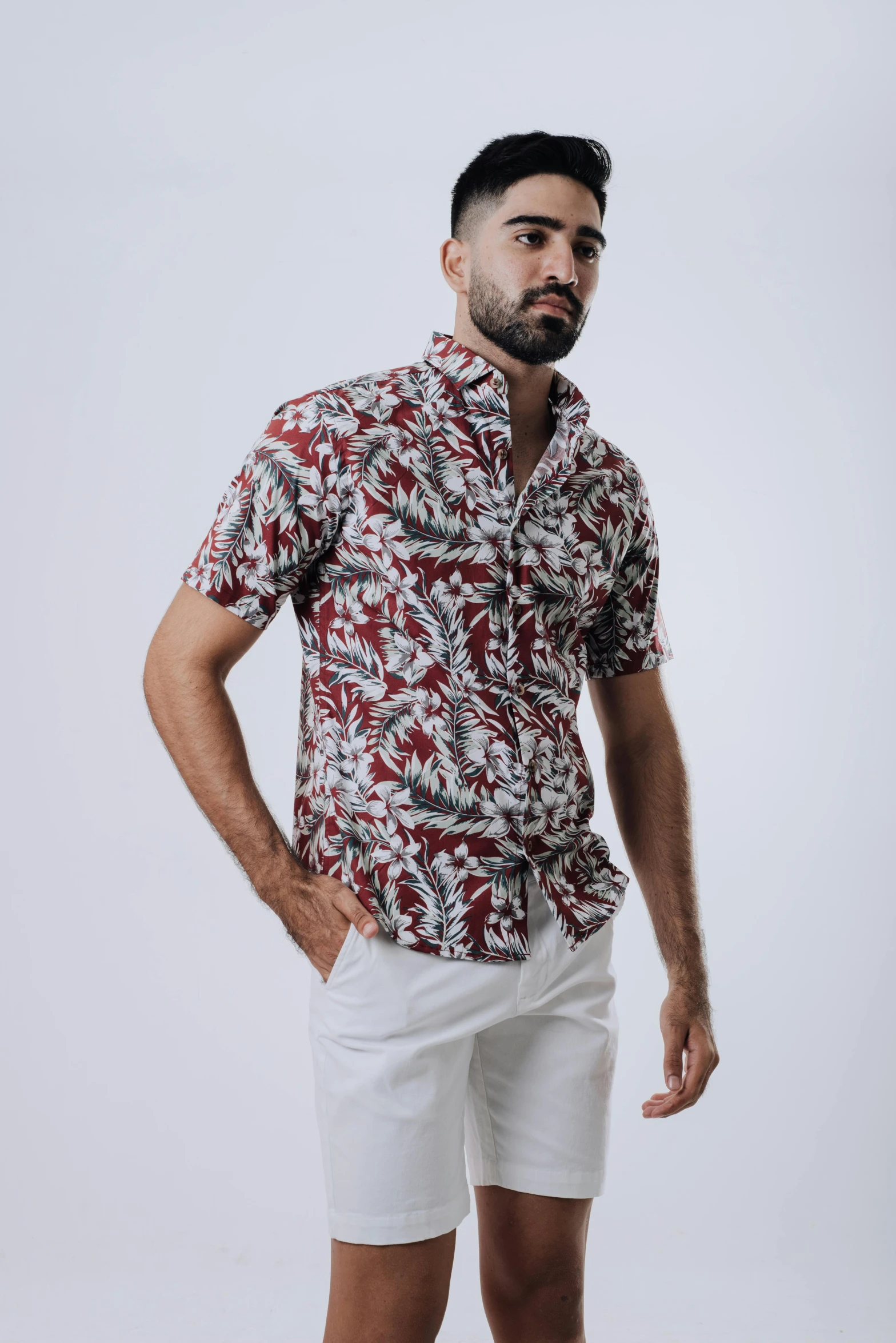 a man wearing white shorts and a shirt with red floral print