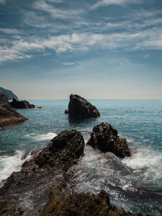 ocean waves roll past rocks on an overcast day