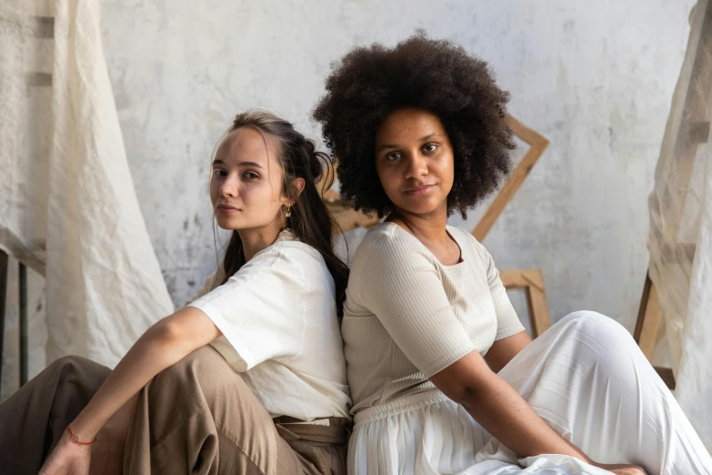 two women sitting next to each other while they both look at the camera