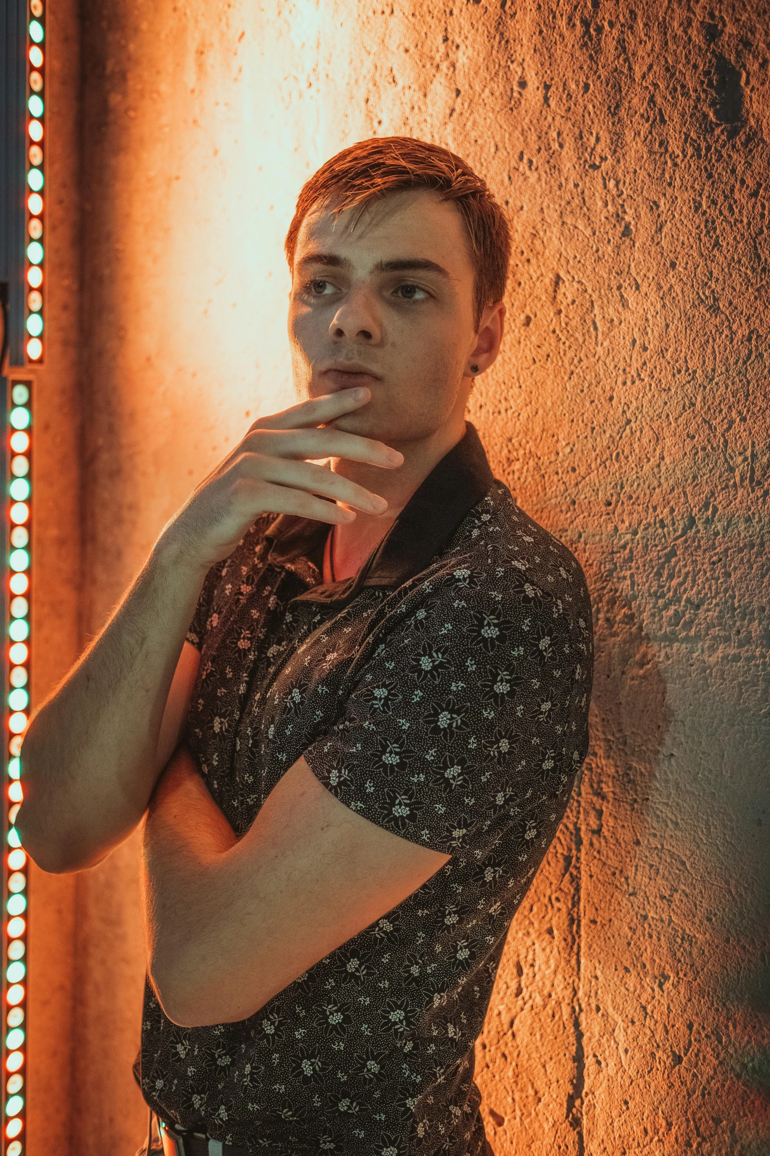 a man standing against a wall with his chin raised