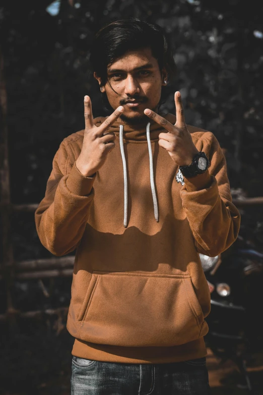 young man in brown jacket making victory sign for peace sign