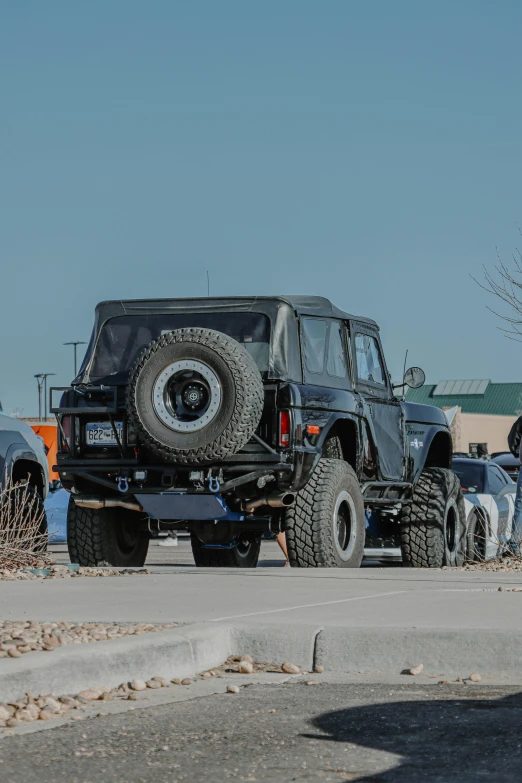 a jeep with an off - road tire is driving in the parking lot