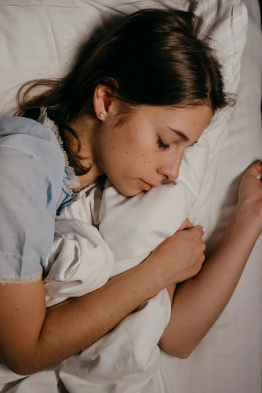 a girl lays down with her arms around a pillow