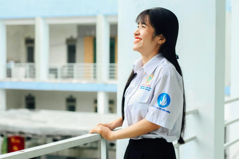 the young woman in uniform is standing by the balcony railing