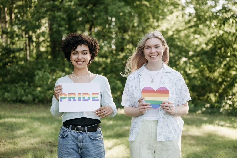 two girls holding up a pride heart shaped cutout