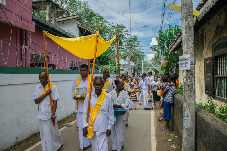 several men carrying yellow flags down a narrow street