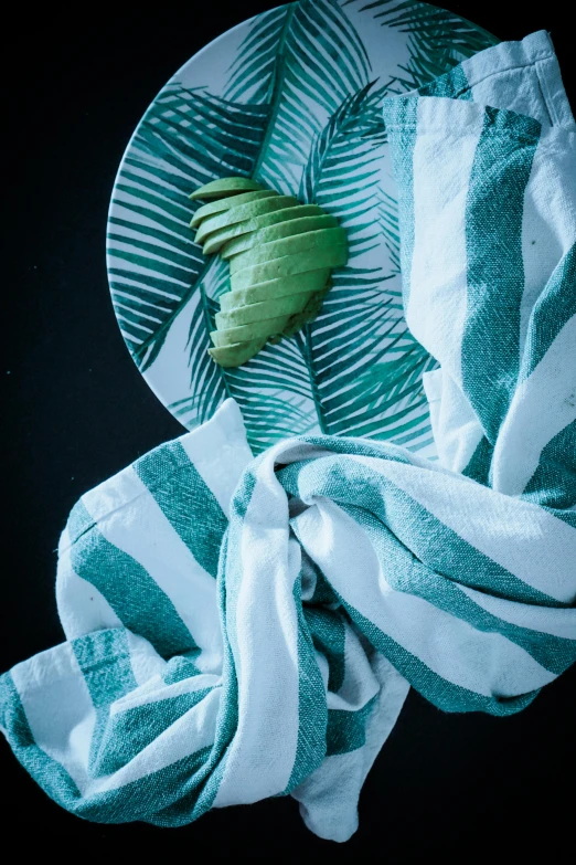 a striped dish sitting on a plate with a green leaf