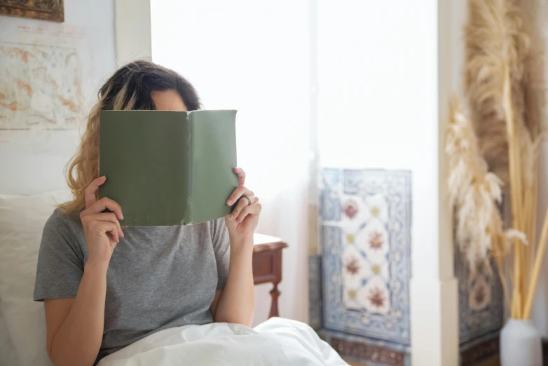 a woman sitting in bed and looking at an open book