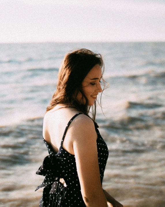 a woman standing on the beach next to the ocean