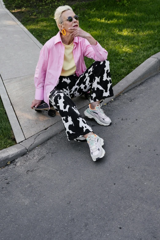 a person sitting on the side of a street with their legs crossed