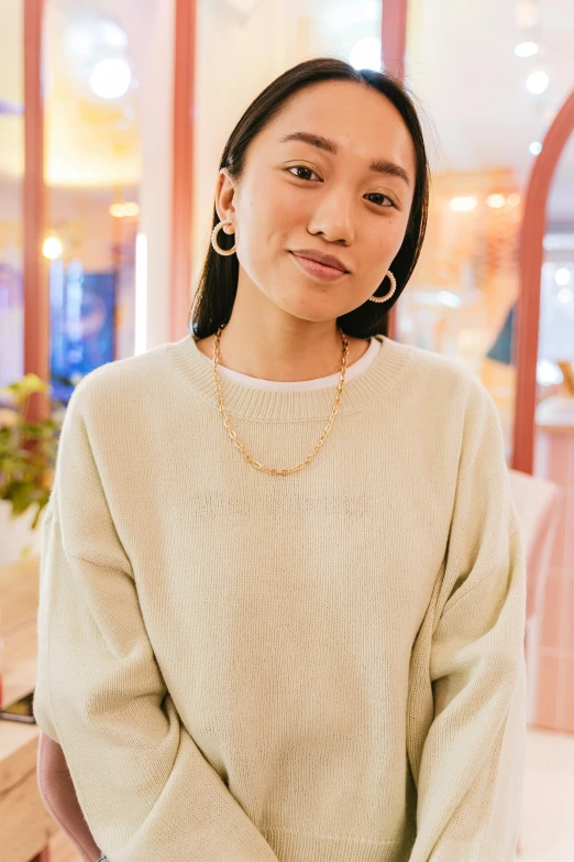 the young woman wears a sweater with earrings