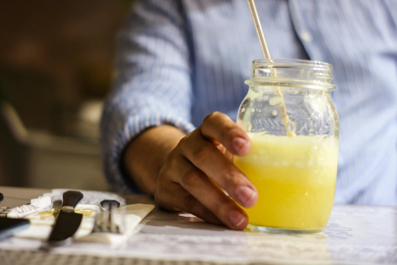 a person holding a glass with yellow liquid in it