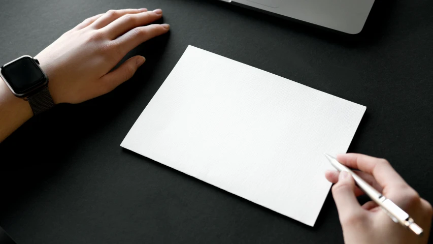 two people are writing on a piece of paper on the table