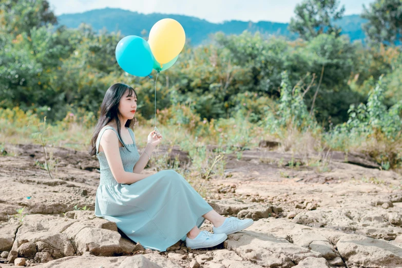 a woman sitting in the sand with a balloon