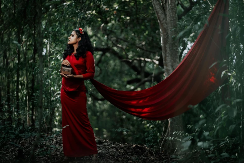 a woman in red with black hair holds up a red cloth