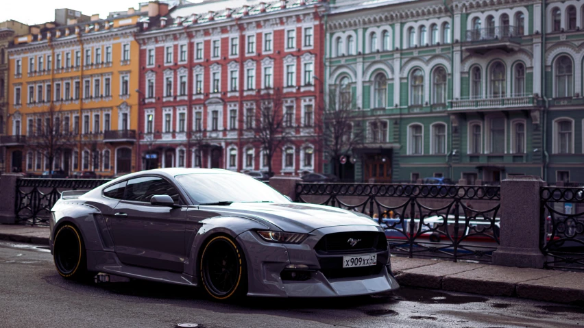 grey sports car parked on side of road near several buildings