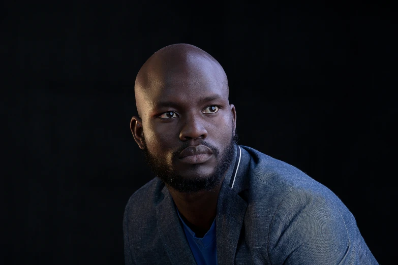 a black man with a bald head, wearing a blue jacket