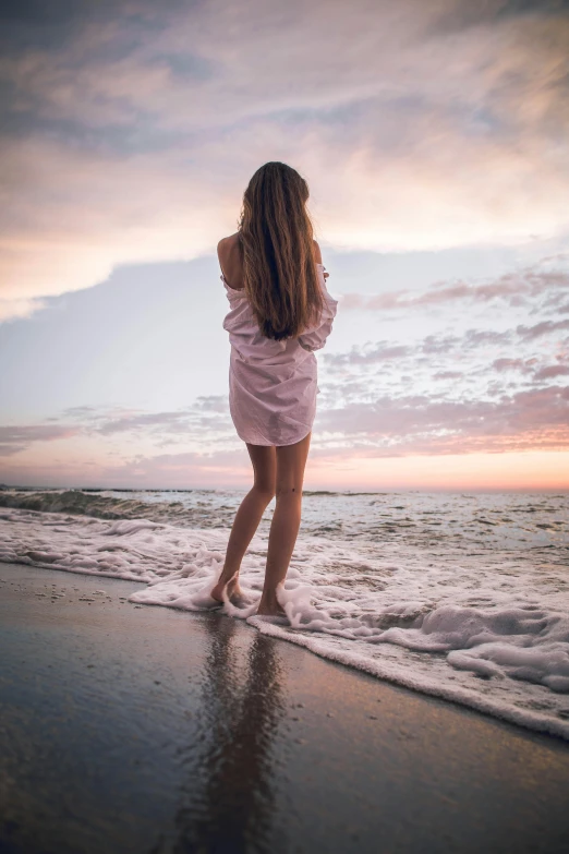 the woman is standing in front of the water on the beach