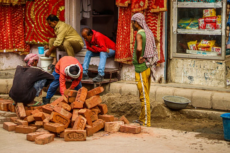three men building brick structure outside a store