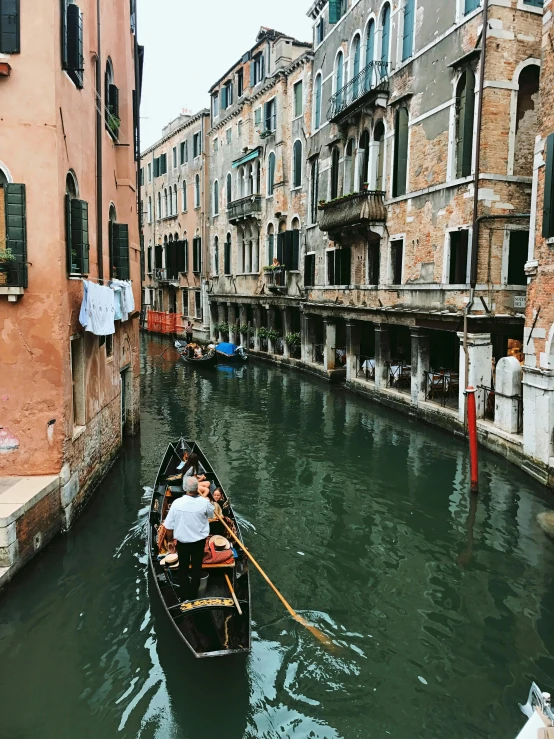 a person in a gondola going down a narrow canal