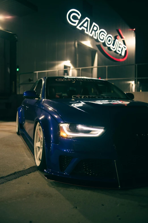 this blue car is parked outside the garage