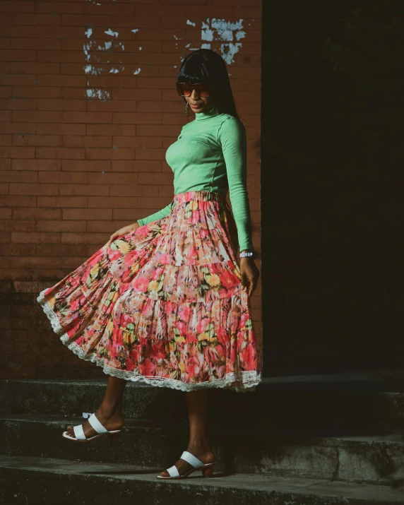 a woman wearing an orange and pink flowered skirt is posing