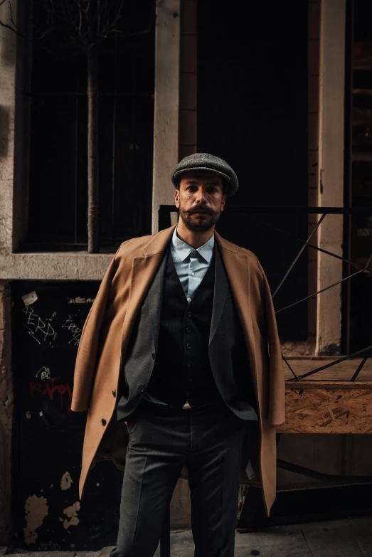 a man with a coat and hat standing in the street