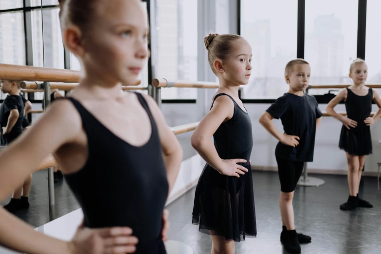 a group of girls in black leorbies standing in front of a window