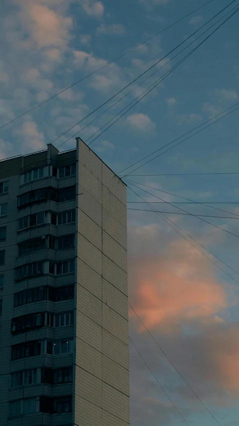 high - rise building with power lines against a colorful sky