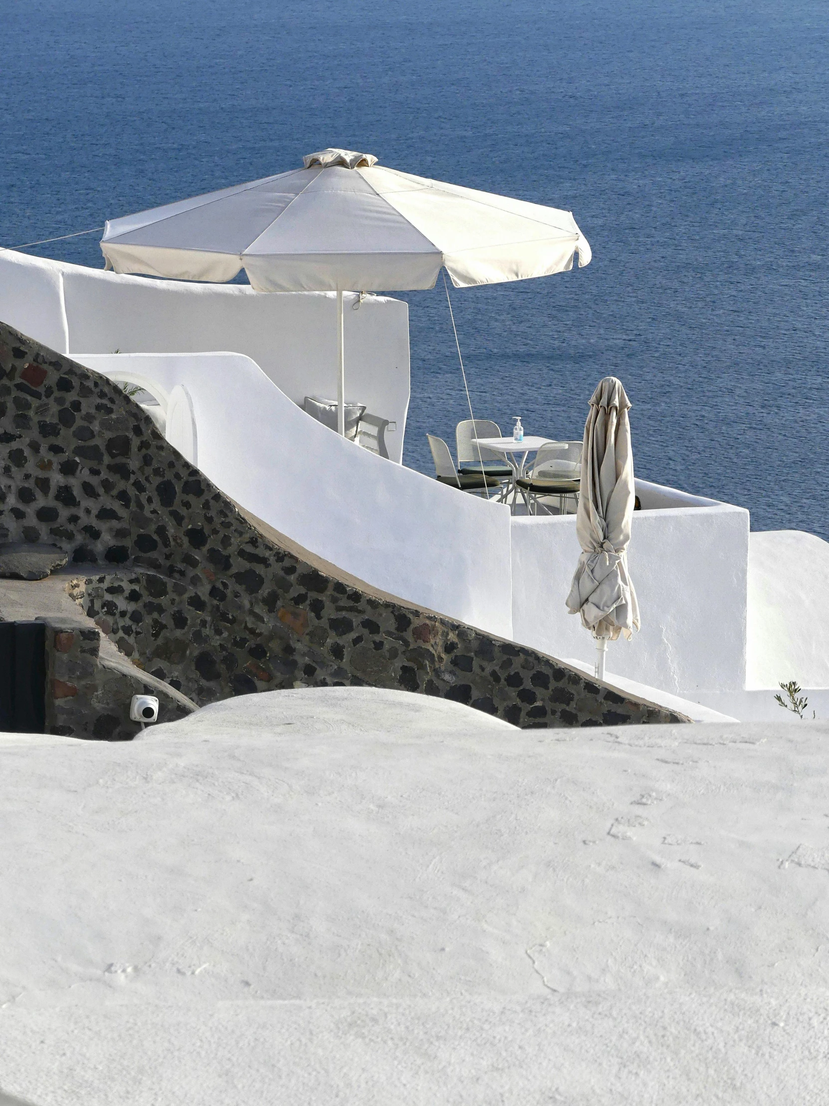 some white tables chairs an umbrellas and water