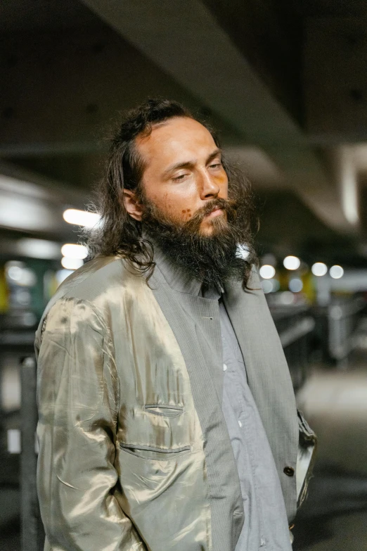 a man standing in a parking garage, wearing a jacket