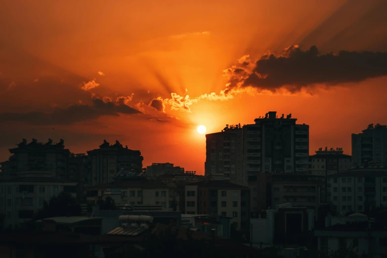 the sun is setting in a cloudy sky over the city