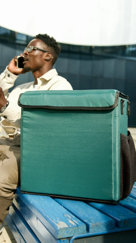 the man is talking on the phone and sitting with luggage