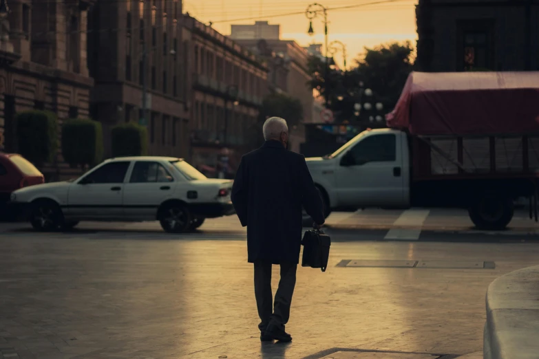 a man in black coat holding his suitcase down the street