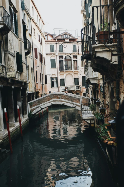 small water canal in urban area, with bridge crossing between buildings