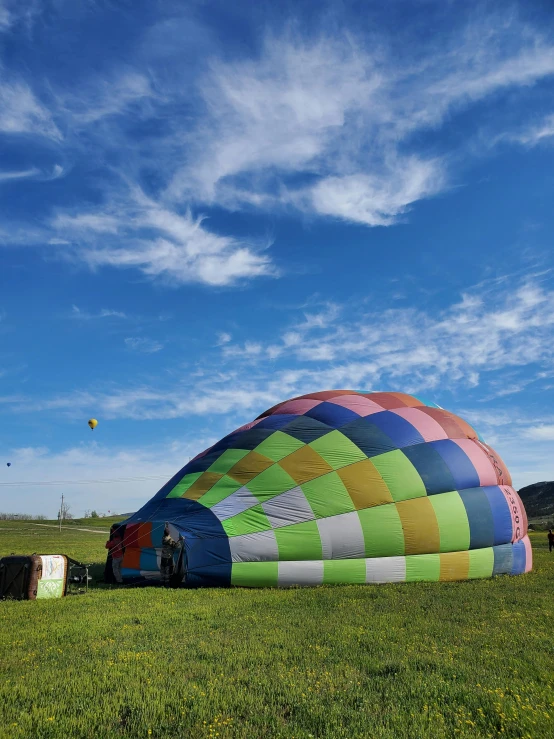 a large colorful air ballon sitting in the middle of a field