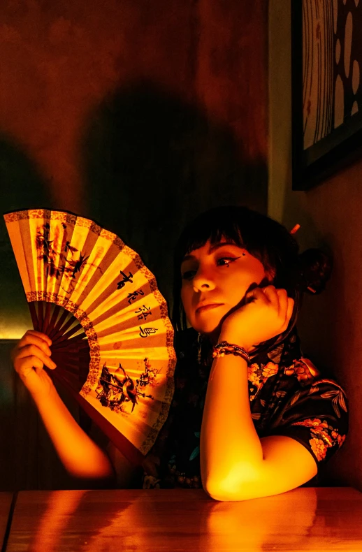 a person sitting down holding an orange fan