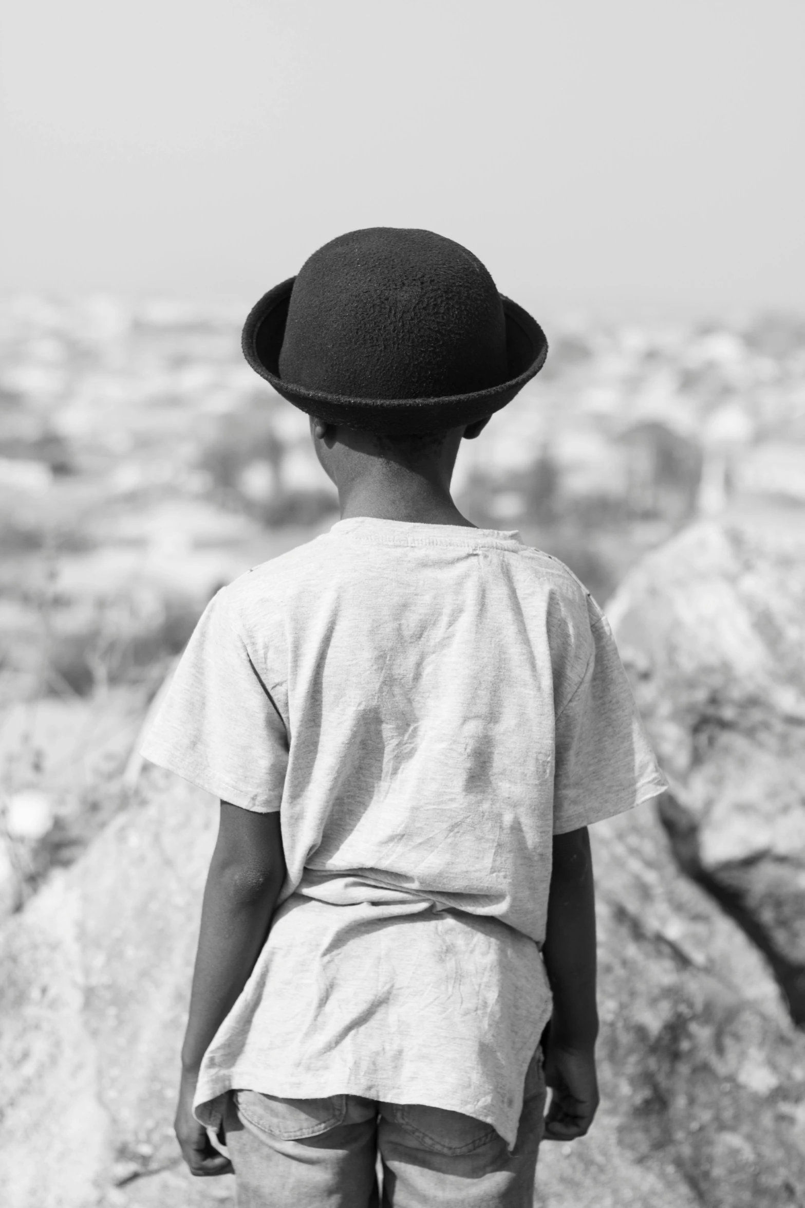 the child is wearing a hat as he looks at the rocky area