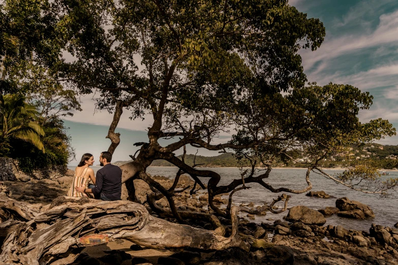 a couple sits on the rocks with trees in the background