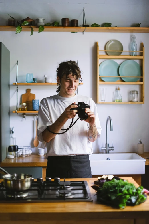 a woman taking a po in the kitchen while holding a camera