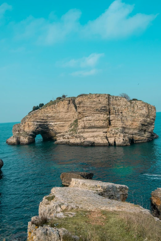 a rock formation near the water with an arch on it