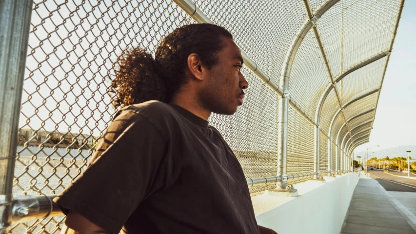 a man standing next to a fence near the ocean