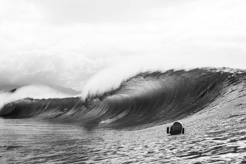 a large wave crashing into a shore next to a lifeguard with two people sitting on the beach