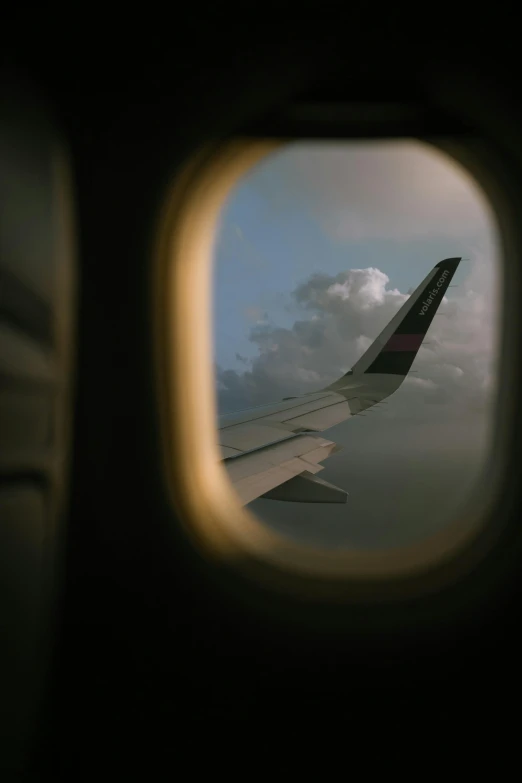 looking out an airplane window at clouds and plane tail