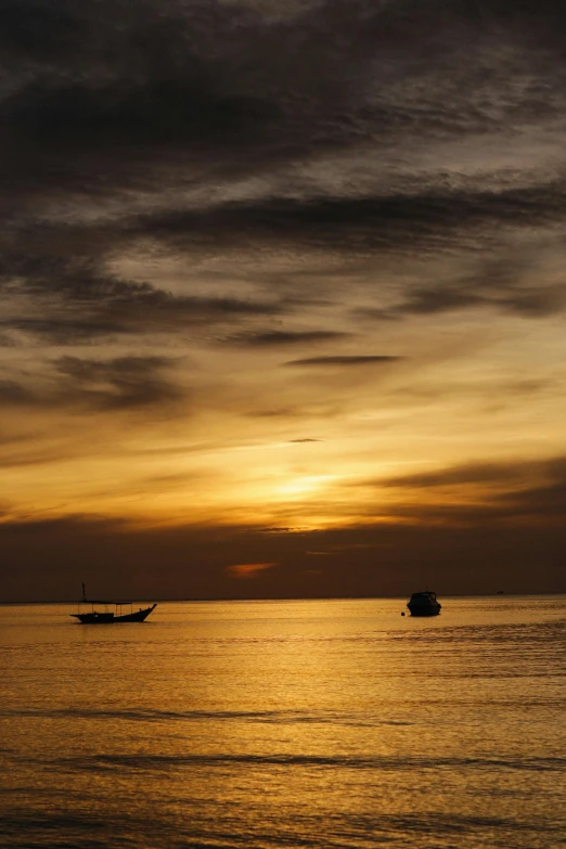 two boats in the water at dusk, with a yellow and black sky above