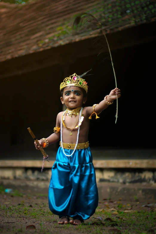 a  wearing a blue dress and some kind of headdress with a rope on his neck and arm