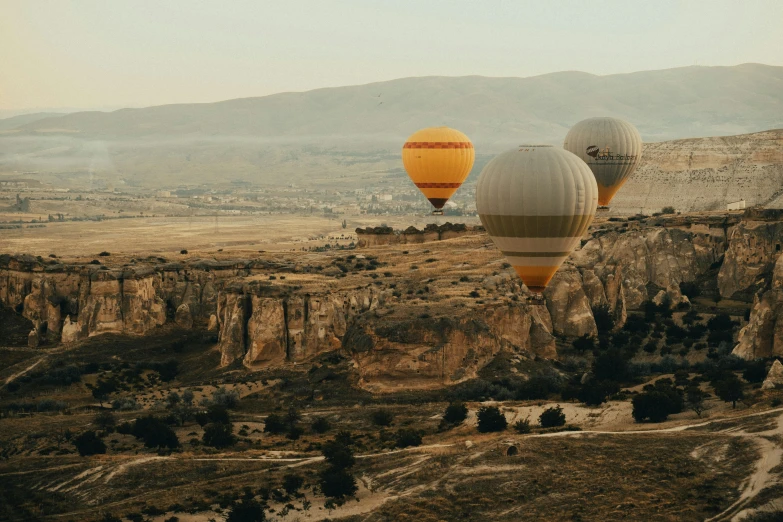 three balloons flying over a mountainous mountain landscape