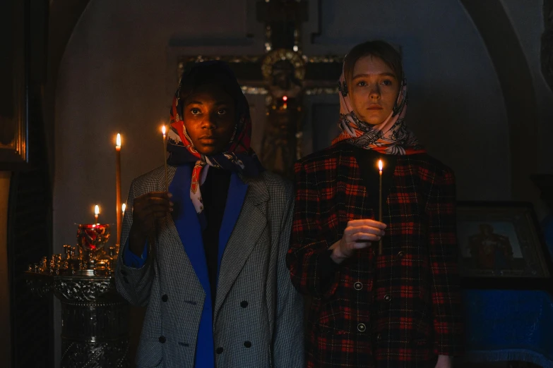 two people standing in a building with candles in their hands